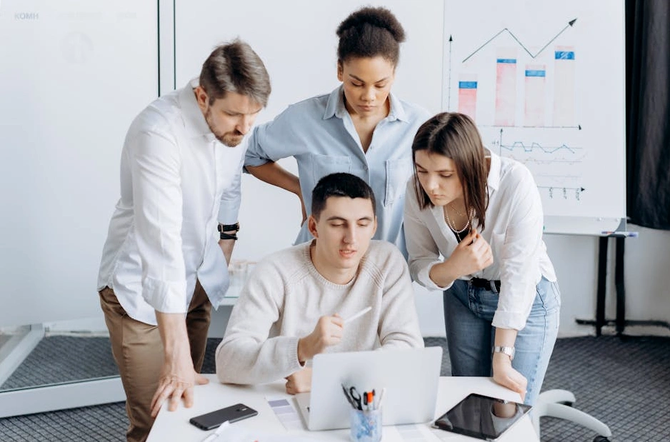 Un team di consulenti analizza diagrammi di flusso su una lavagna bianca.